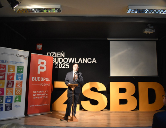 Na czarnym tle sceny przemawia Dyrektor Zespołu Szkół Budowlano-Drzewnych