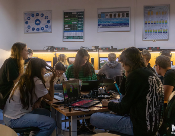 Kółko informatyczne "GITES" w ZSE nr 2 Na grafice znajduje się młodzież, siedzą w klasie szkolnej i pracują na sprzęcie komputerowym