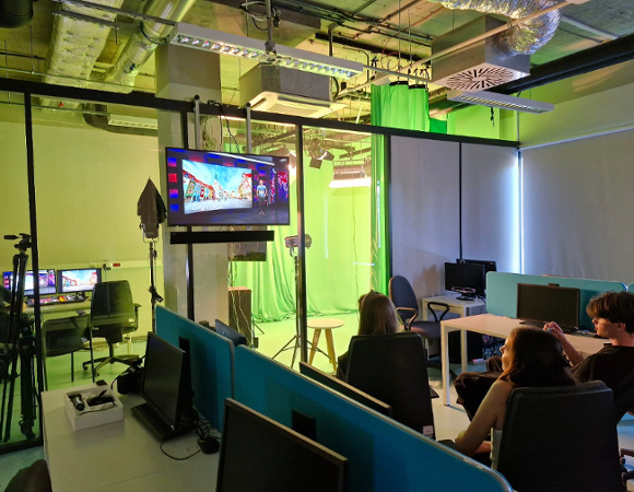 Na zdjęciu młodzi ludzie w laboratorium IT, uczą się z wykorzystaniem programu wyświetlanego na ekranie telewizora.