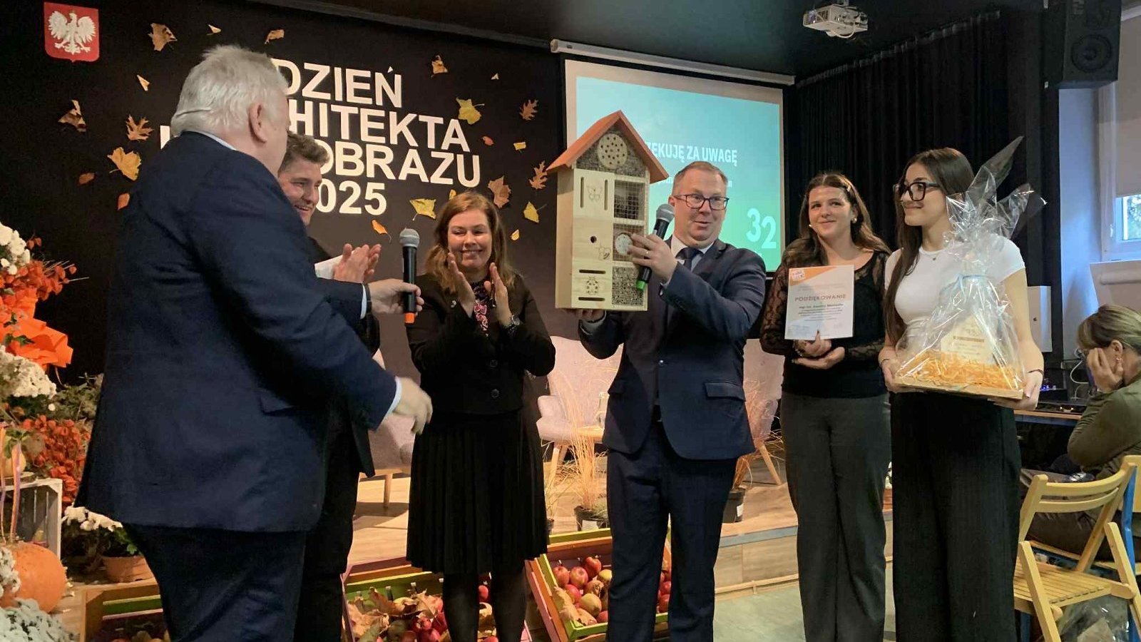 Na zdjęciu znajduje się uczestnicy wydarzenia, między innymi Dyrektor szkoły, trzymający w ręku domek dla owadów.