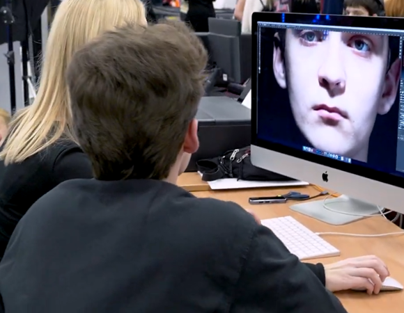 Osoba przy komputerze edytuje zdjęcie twarzy na ekranie.